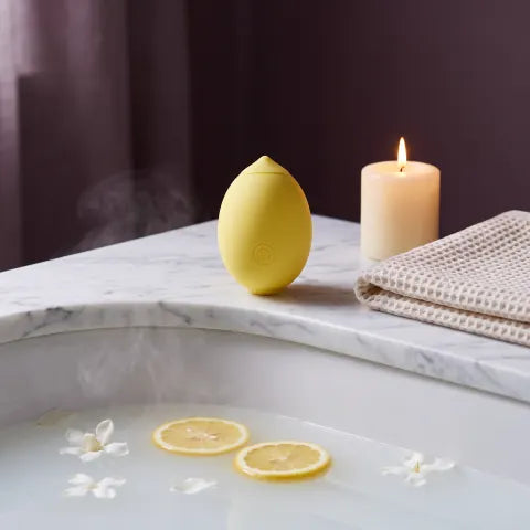 The Limone on a marble bathtub edge with a candle and towel