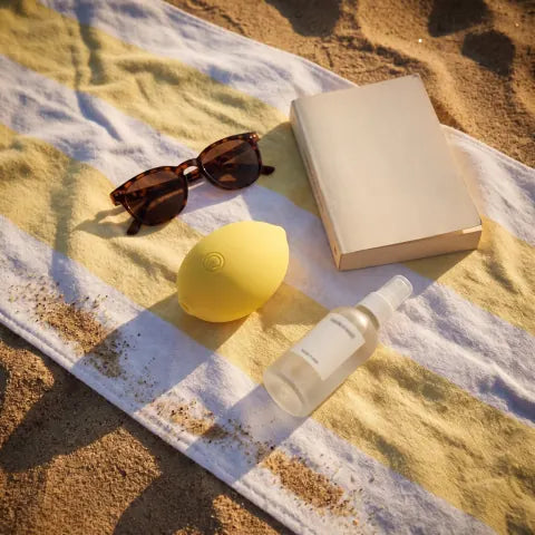 The Limone on a striped beach towel with sunglasses and a book