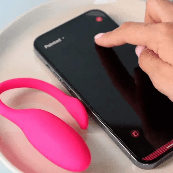 A hand controlling the app on a phone next to the Flamingo device