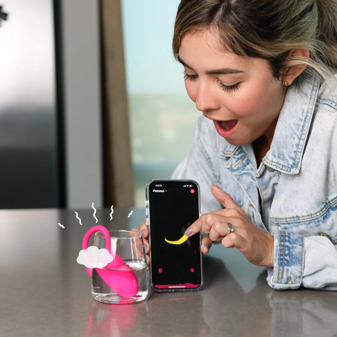 Woman reacting with surprise to her phone as the Flamingo buzzes in a glass of water